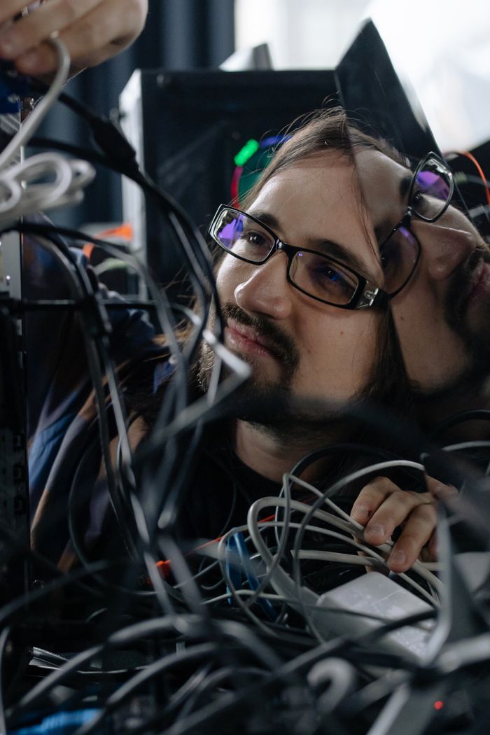 our-story A focused male system administrator adjusting tangled network cables indoors.